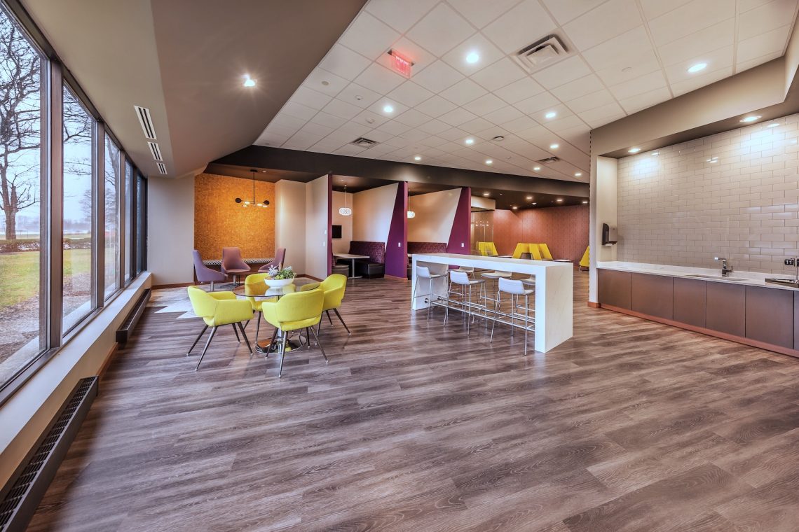 Social hub seating area and meeting spaces with collaborative booths and a glass enclosed meeting table