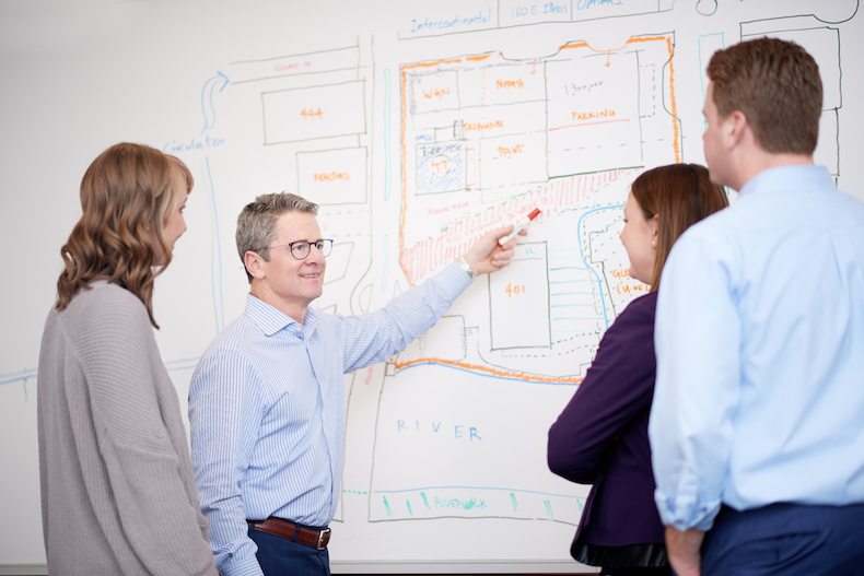 Zeller commercial property manager employees discussing a project in front of a whiteboard.